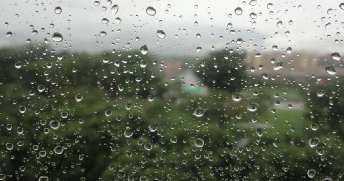 Cristal de ventana con gotas de lluvia y paisaje nublado en Sinaloa