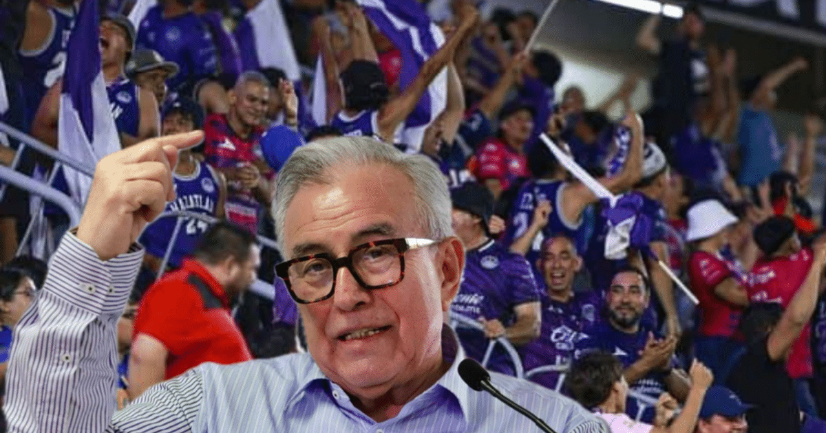 Aficionados vibrantes animando con banderas en un partido de Mazatlán FC, destacando un hombre con gafas al frente.