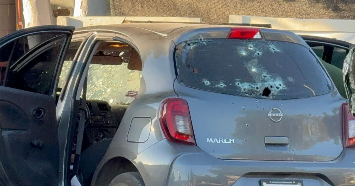 Nissan March con agujeros de bala y puerta abierta en Culiacán