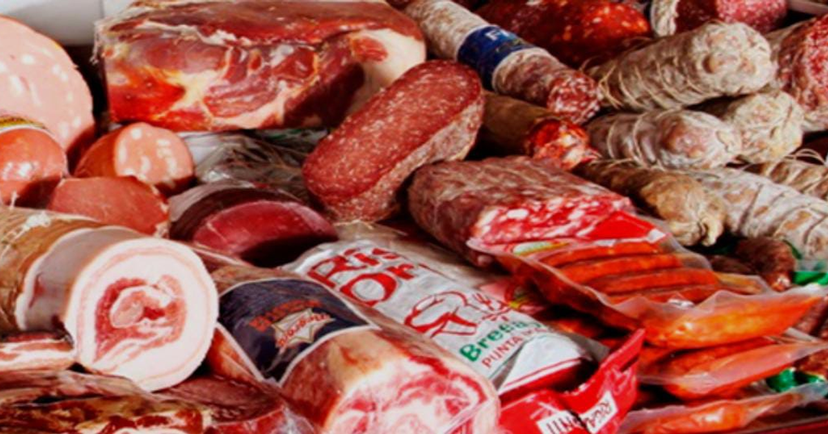 Selección diversa de embutidos y carnes curadas de diferentes colores y texturas sobre una superficie.
