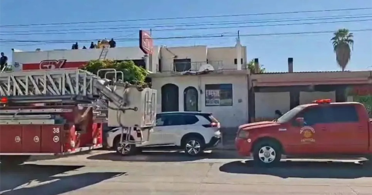 Camión de bomberos y SUV en escena urbana con edificio y personas en el techo, relacionado con accidente eléctrico en Los Mochis.