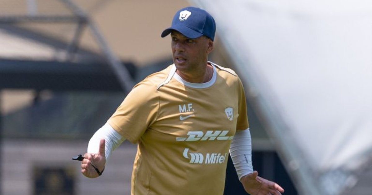 Hombre con camiseta de entrenamiento y gorro dirigiendo práctica de fútbol, posiblemente Marcelo Frigério.