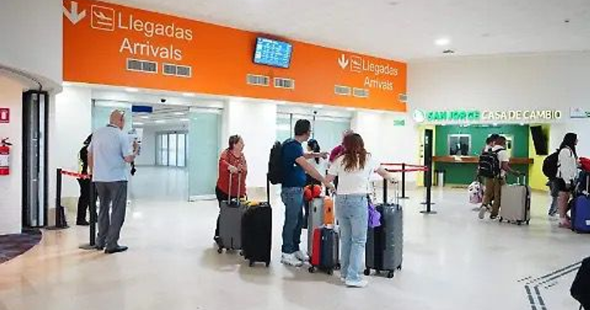 Área de llegadas en el Aeropuerto Internacional de Mazatlán con panel de 'Llegadas' y 'Arrivals', personas con maletas y mostrador de cambio de divisas.