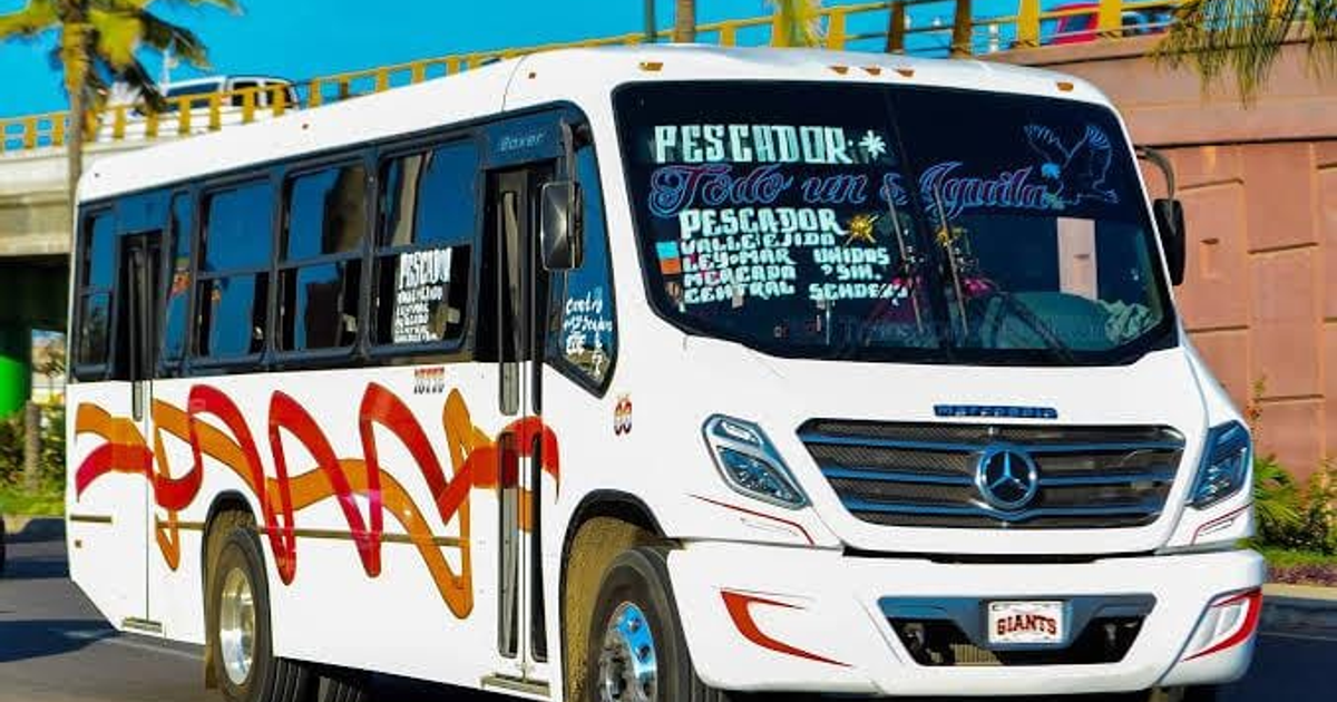 Autobús de la ruta Hogar del Pescador en Mazatlán, Sinaloa, con detalles en rojo y naranja, frente a un puente y palmeras.