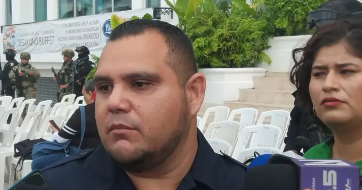 Hombre siendo entrevistado en conferencia de seguridad en Mazatlán, con soldados al fondo.