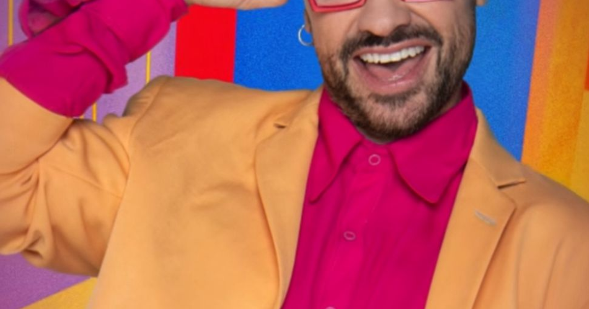 Shiky sonriendo con camisa rosa y saco amarillo, fondo abstracto
