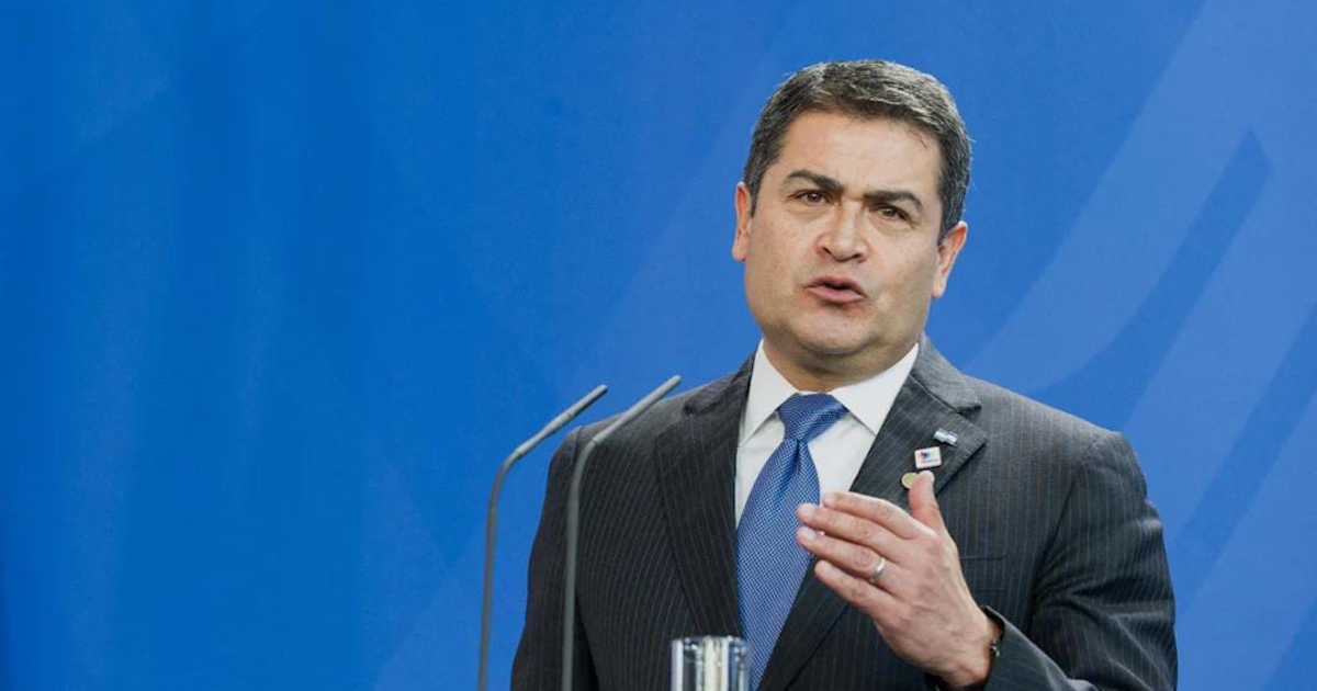 Hombre hablando formalmente con fondo azul relacionado con indulto a Juan Orlando Hernández