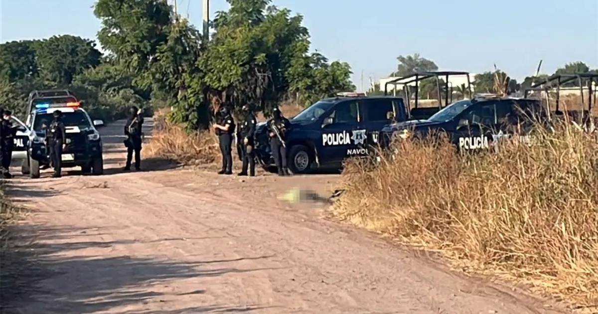 Escena policial en camino de tierra en Sinaloa con un cuerpo y policías presentes.