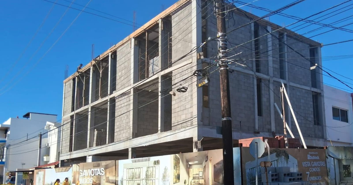 Edificio en construcción con bloques de concreto en Mazatlán y carteles de desarrollo de condominios.