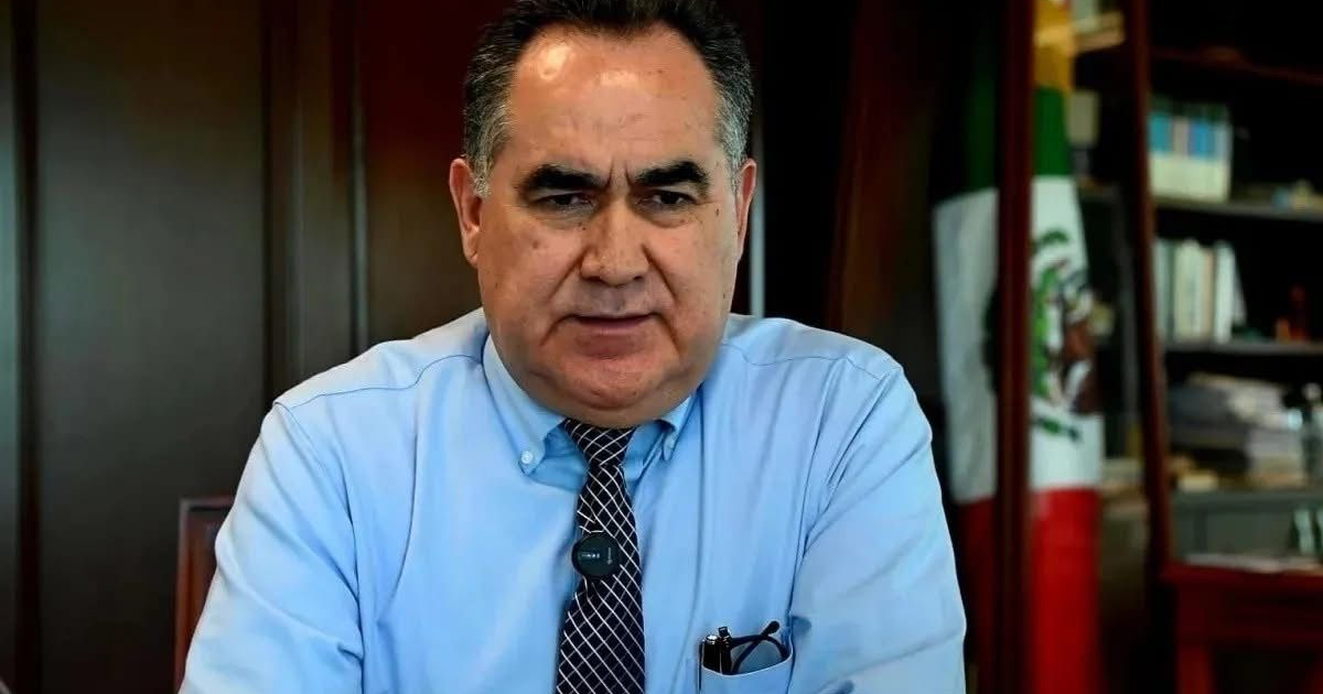 Jesús Madueña Molina, rector de la UAS, en su oficina con bandera mexicana de fondo.