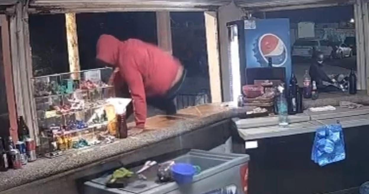 Sujeto con capucha roja salta mostrador en tienda de Los Mochis durante robo.