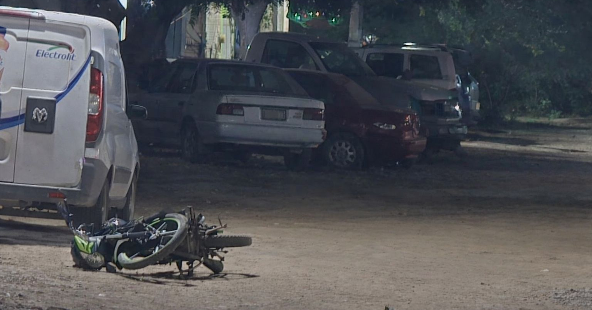 Vehículos estacionados y una bicicleta caída bajo iluminación nocturna en Culiacán