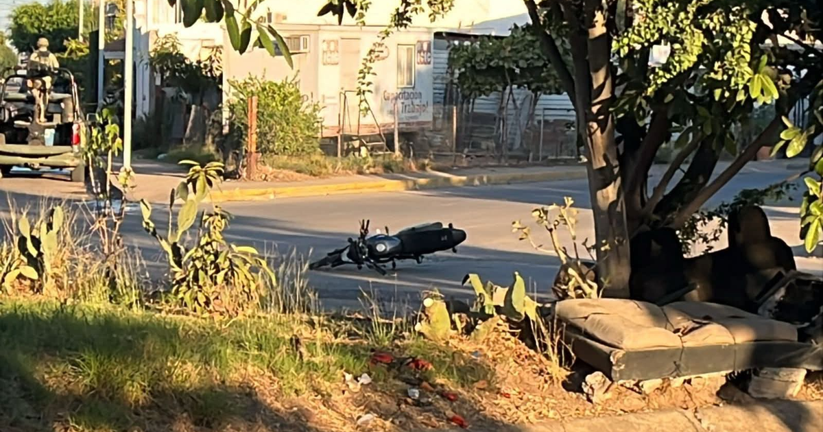 Motocicleta caída en Culiacán tras un ataque armado con una camioneta al fondo.