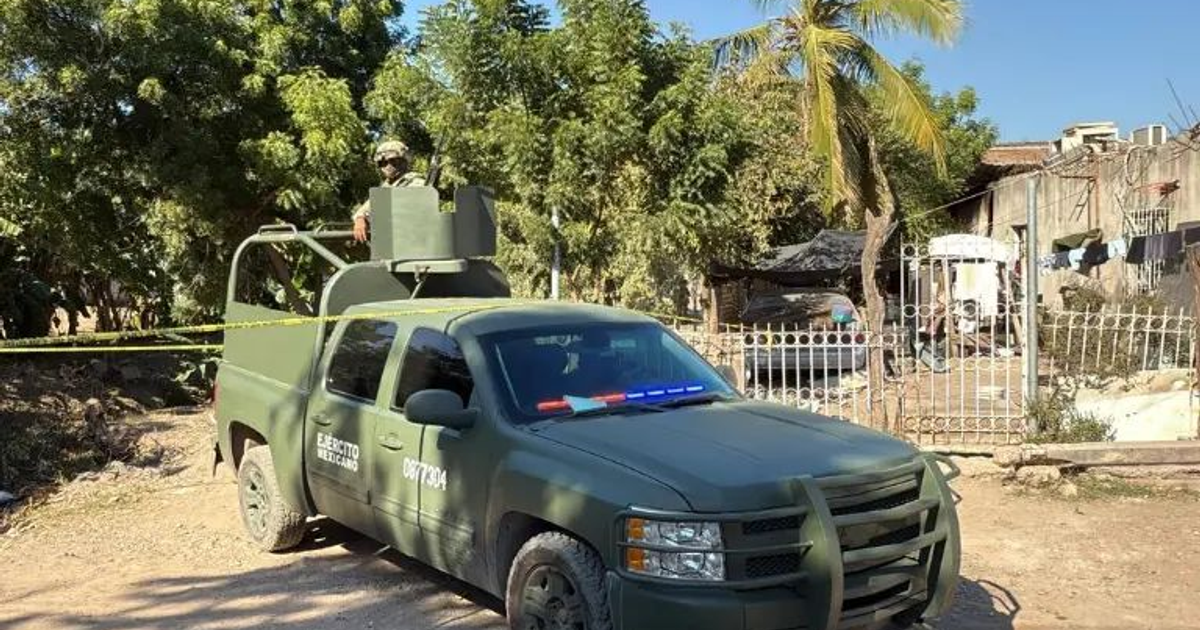 Soldado en vigilancia sobre un vehículo militar mexicano en una zona con cinta de seguridad amarilla.