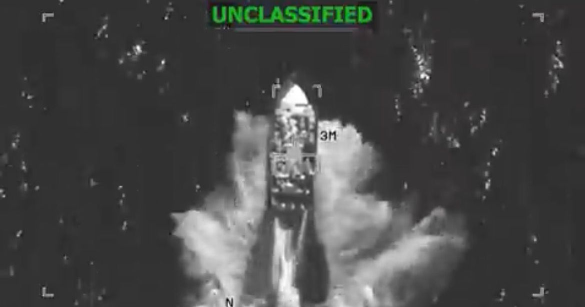 Vista aérea en blanco y negro de un barco en movimiento etiquetado como 'UNCLASSIFIED', posiblemente en una operación militar.