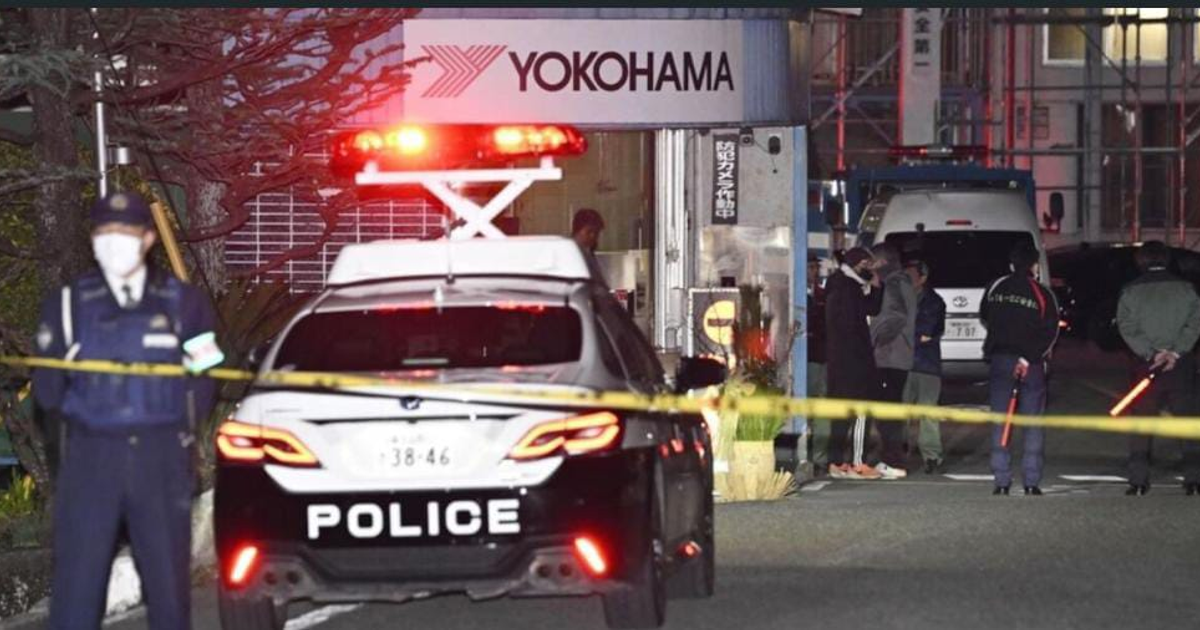 Incidente policial con coche de policía y cintas amarillas en Mishima, Japón, tras un ataque en fábrica.