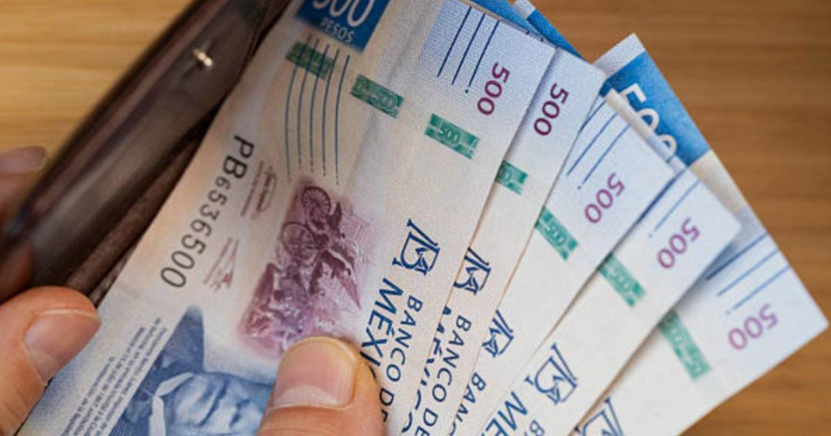 Mano sosteniendo billetes de 500 pesos de una billetera, aumento salarial en México 2026.