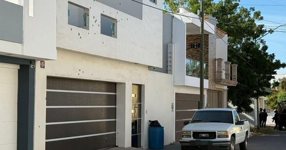 Calle Paricutín tras ataque armado en Rincón del Humaya, mostrando un edificio dañado, un vehículo blanco y presencia policial.