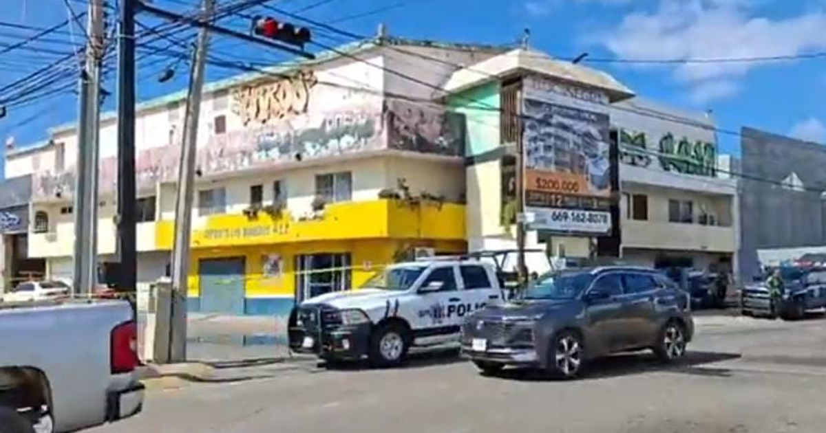 Intersección en Mazatlán con camioneta de policía y edificio amarillo al fondo