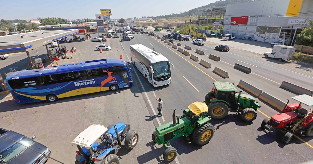 Tractores bloquean vía urbana en protesta agroalimentaria con una estación de servicio al costado.
