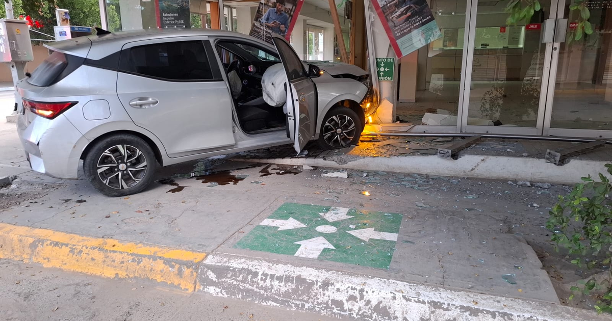 Automóvil chocado contra un banco con puerta del conductor abierta y vidrios rotos alrededor en Guasave, Sinaloa.
