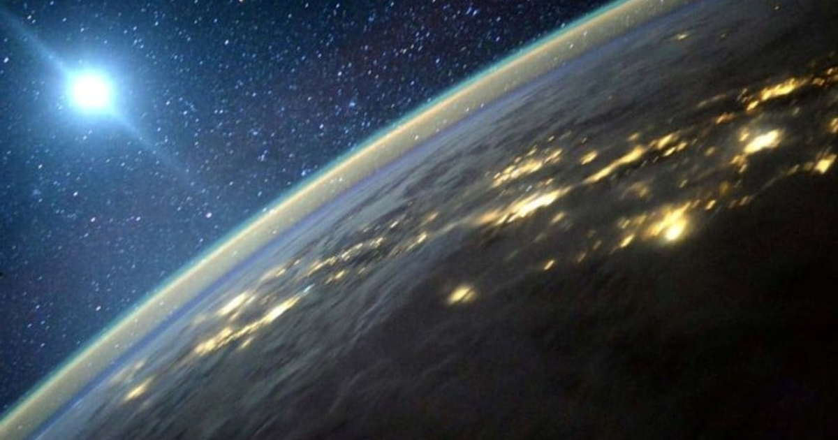 Vista de la Tierra desde el espacio con fondo estrellado y luces en la superficie.