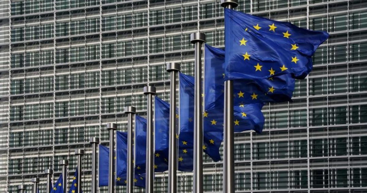 Banderas de la Unión Europea ondeando frente a un edificio moderno.