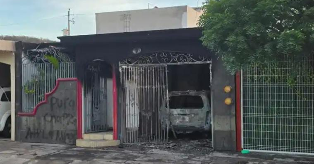 Casa dañada tras ataque en Culiacán: Entrada con barrotes deformados y vehículo quemado.