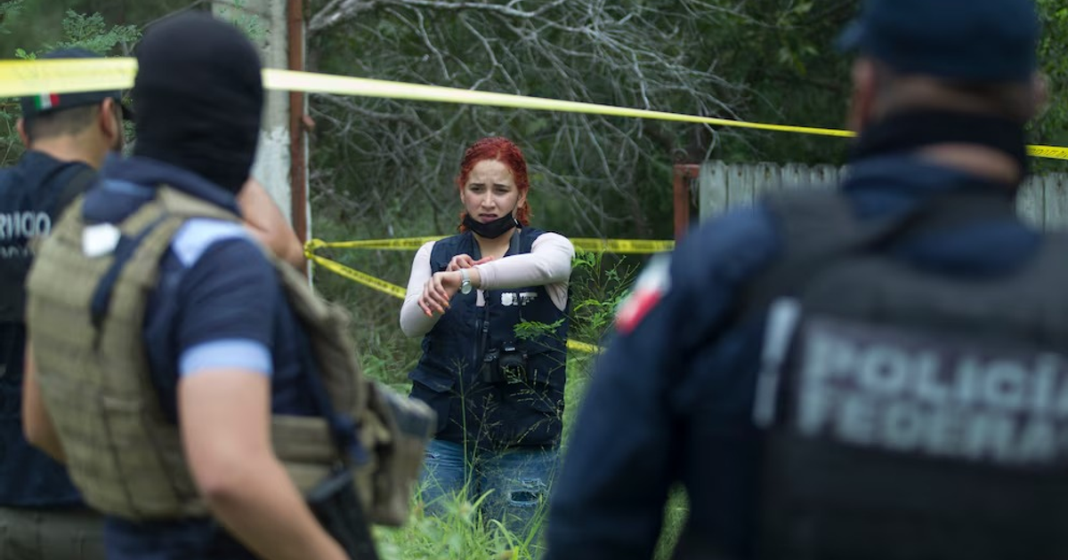 Operativo policial en Reynosa durante marcha por desaparecidos, con oficiales en uniforme y cinta amarilla en un entorno natural.