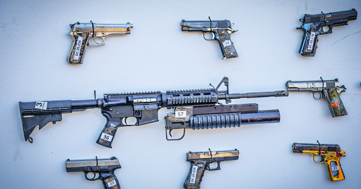 Serie de armas de fuego decomisadas en Culiacán, incluyendo un rifle central y pistolas etiquetadas, sobre un fondo claro.