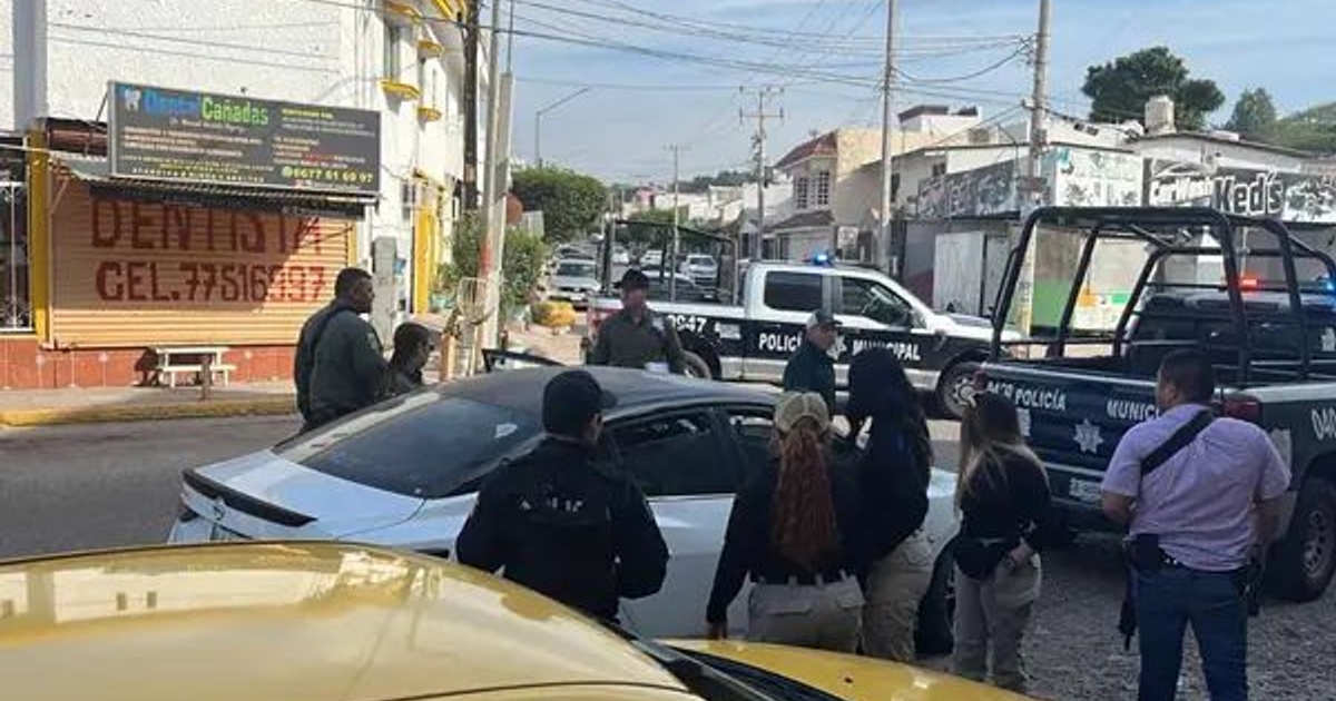 Policías y vehículos patrulla en una escena de seguridad en Culiacán, en torno a un automóvil blanco tras un ataque armado.