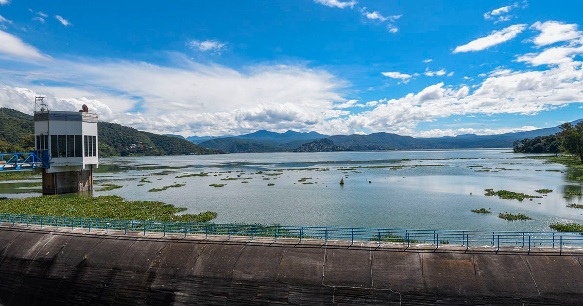 Cuerpo de agua en un entorno montañoso con una torre de control y cielo despejado