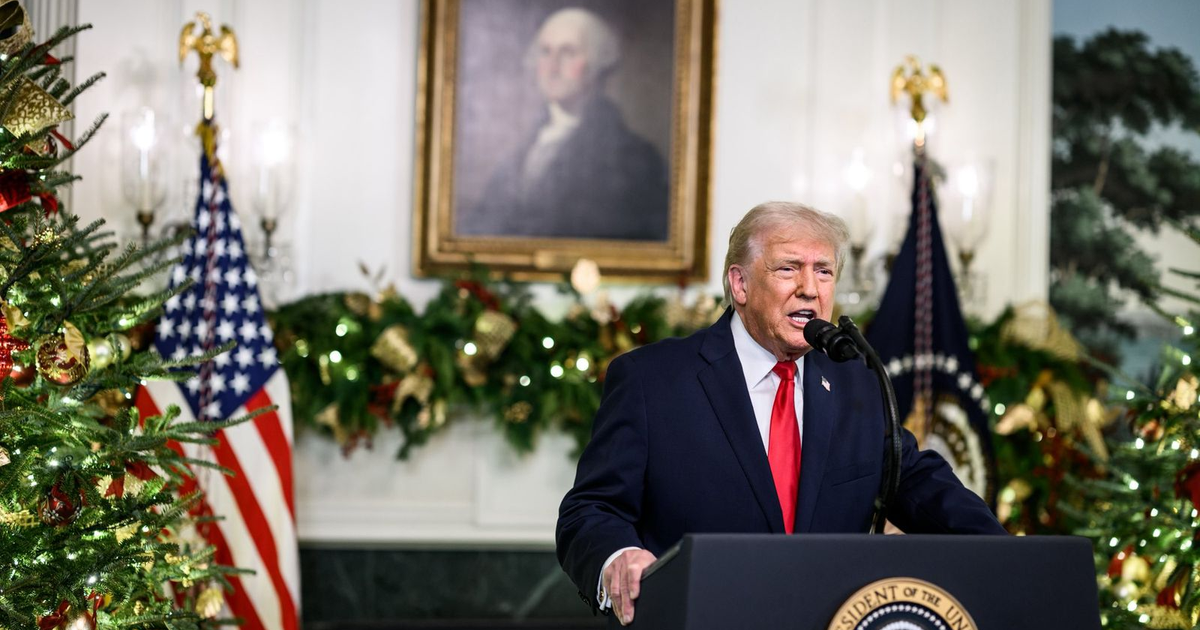 Donald Trump hablando en un evento navideño en la Casa Blanca delante de un árbol de Navidad.