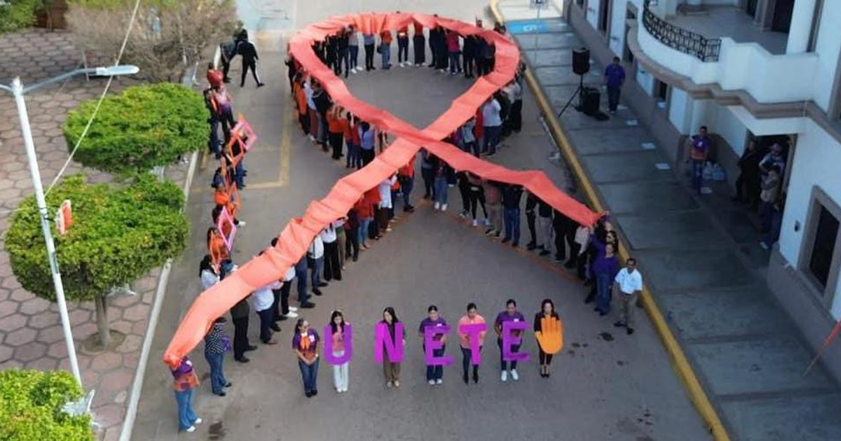 Grupo de personas formando un lazo naranja con pancartas 'ÚNETE' en Elota