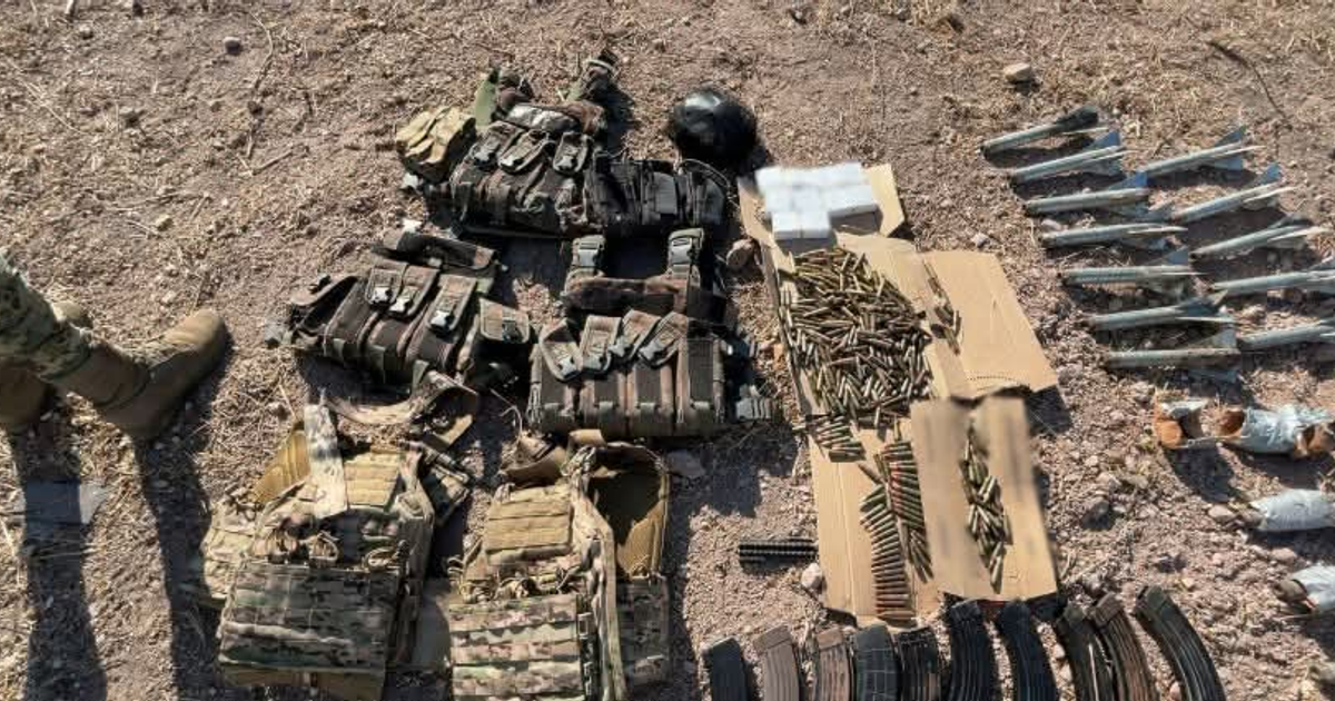 Equipo militar incautado en Escuinapa: chalecos tácticos, casco y municiones sobre suelo de grava.