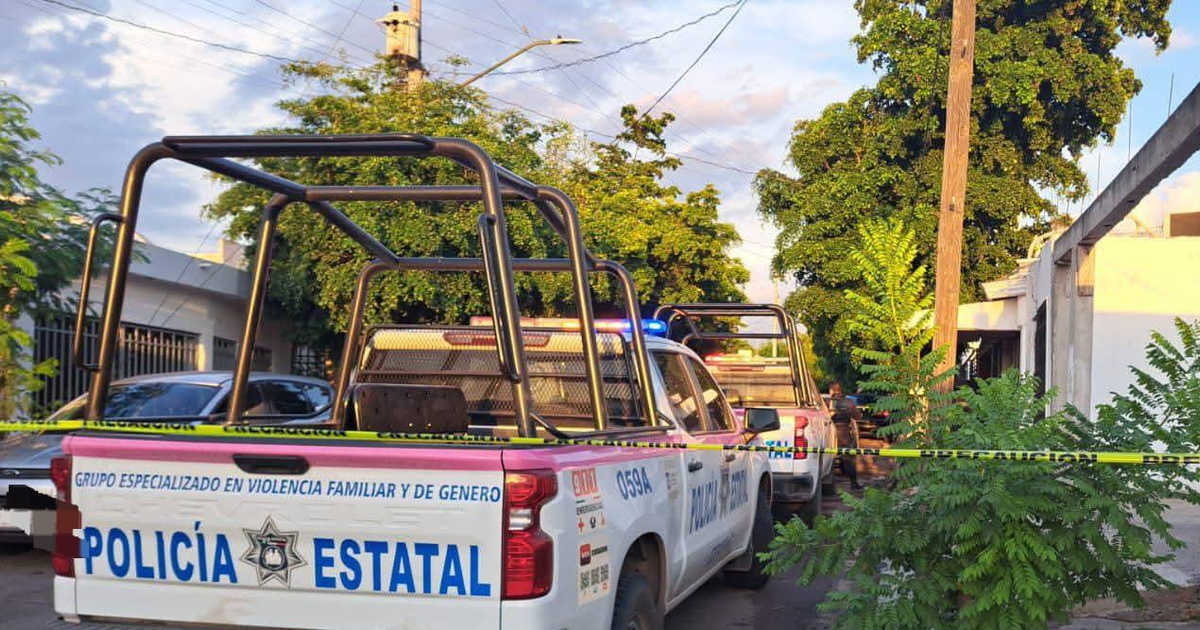 Camionetas de la Policía Estatal estacionadas, cinta de precaución y vegetación en una calle urbana.