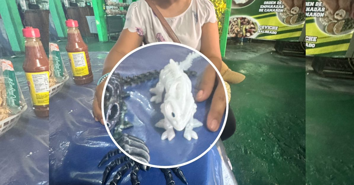 Figura 3D de iguana sobre tela decorativa en una mesa de mercado, con botellas y plato de comida.