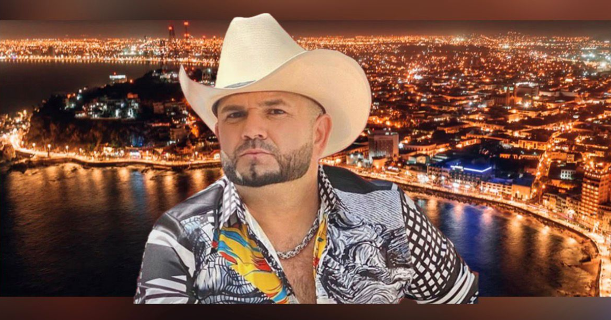 Hombre con sombrero en un paisaje nocturno costero, ciudad iluminada y agua al fondo