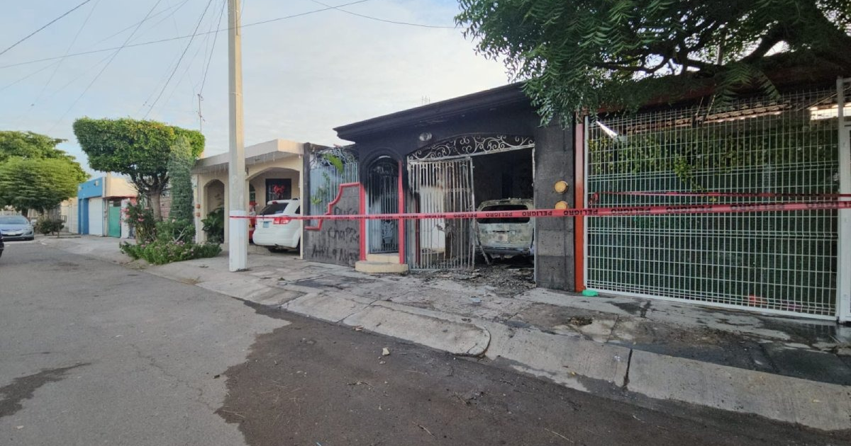 Imagen de calle residencial con casa dañada por incendio en Culiacán, acordonada con cinta de seguridad y vehículos estacionados.