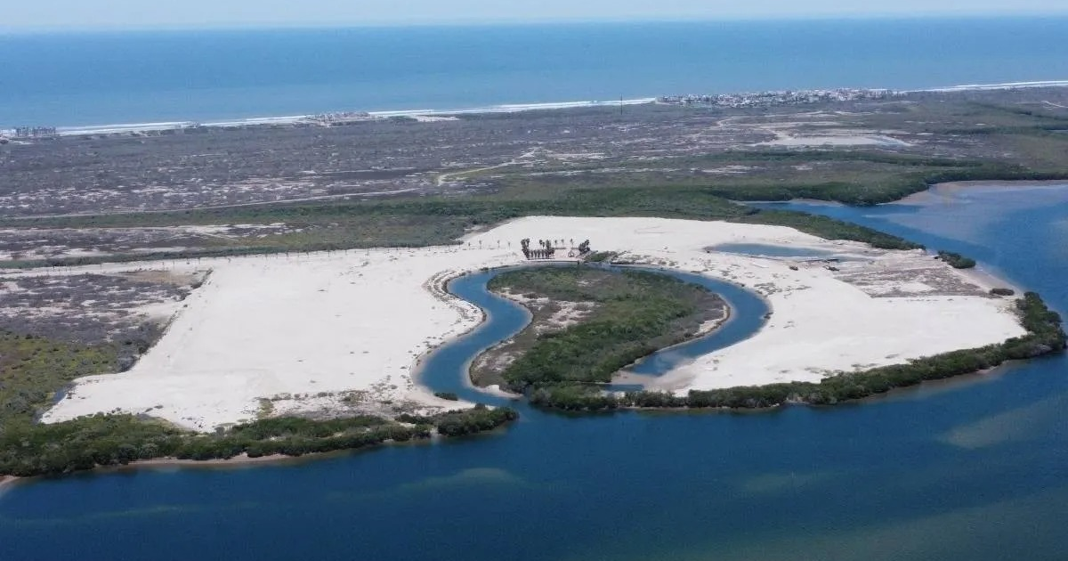 Paisaje aéreo de urbanización en desarrollo en Isla Cortés, Sinaloa, sin permisos municipales aprobados, destacando áreas costeras, agua y vegetación.