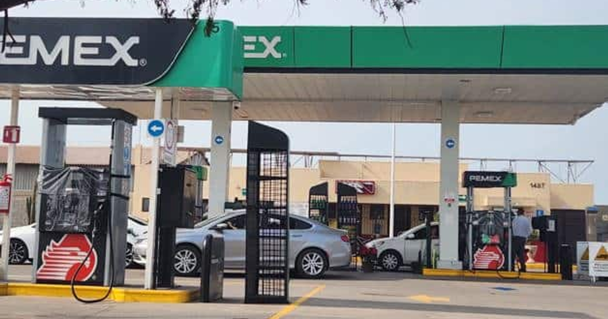 Gasolinera Pemex en área urbana con autos y bombas de gasolina visibles.