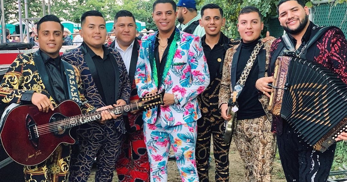 Grupo Firme posando juntos con trajes coloridos e instrumentos, anticipándose al 'La Última Peda Tour 2026'.