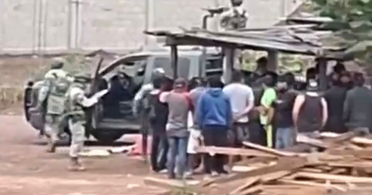Militares y civiles reunidos revisando una camioneta en una operación de seguridad.