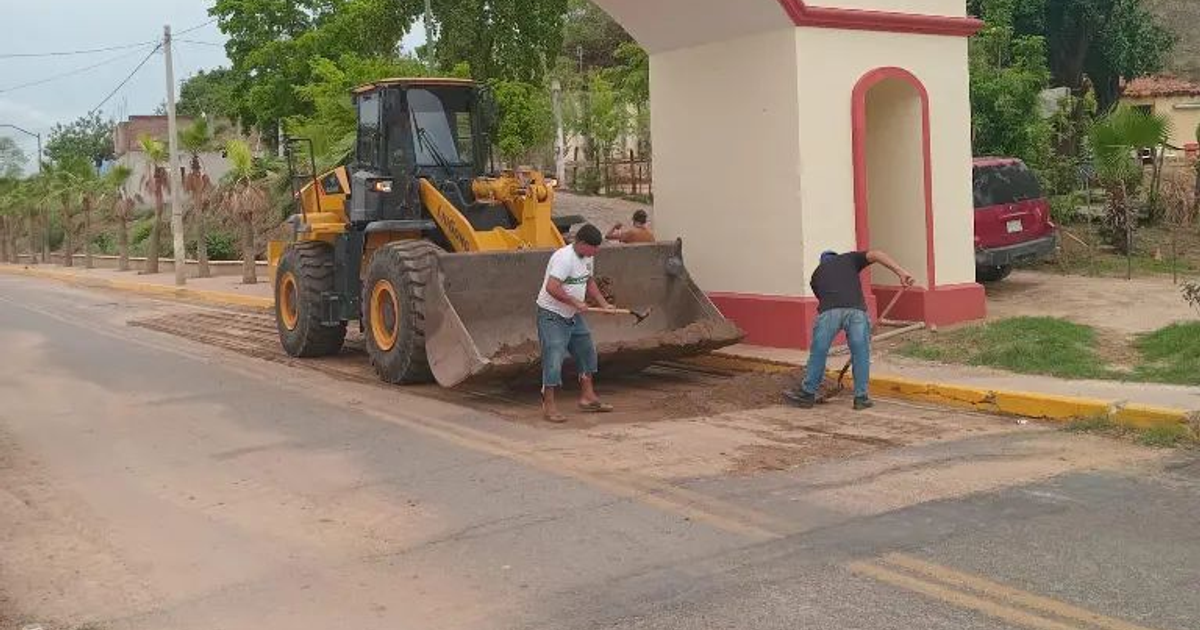 Trabajadores en la vía pública con retroexcavadora durante labores de mantenimiento