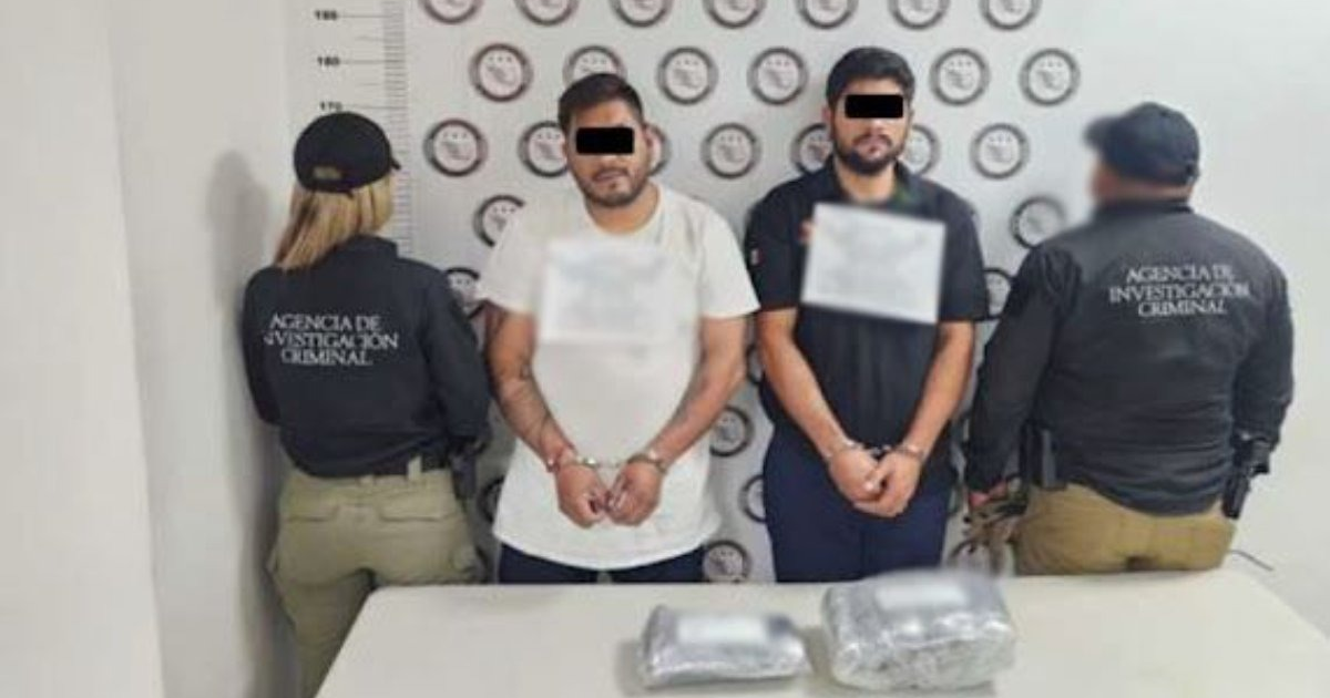 Dos detenidos en estación de Guasave esposados frente a paquetes incautados por agentes.