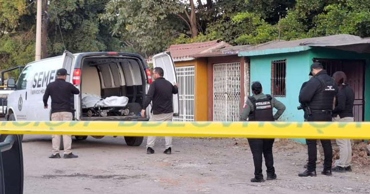Escena del crimen acordonada en Villa Juárez con vehículo del SEMEF y casas urbanas de fondo.