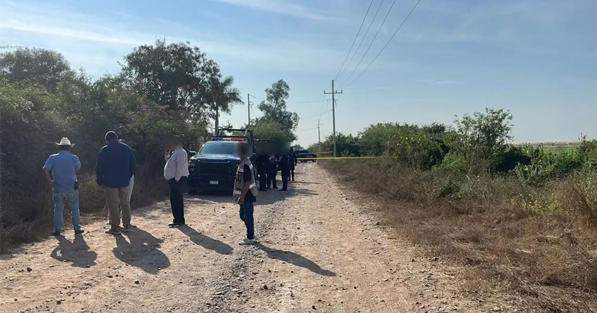 Camino de terracería con vehículos de policía y personas en La Sinaloa, Navolato, donde ocurrió un hallazgo criminal.