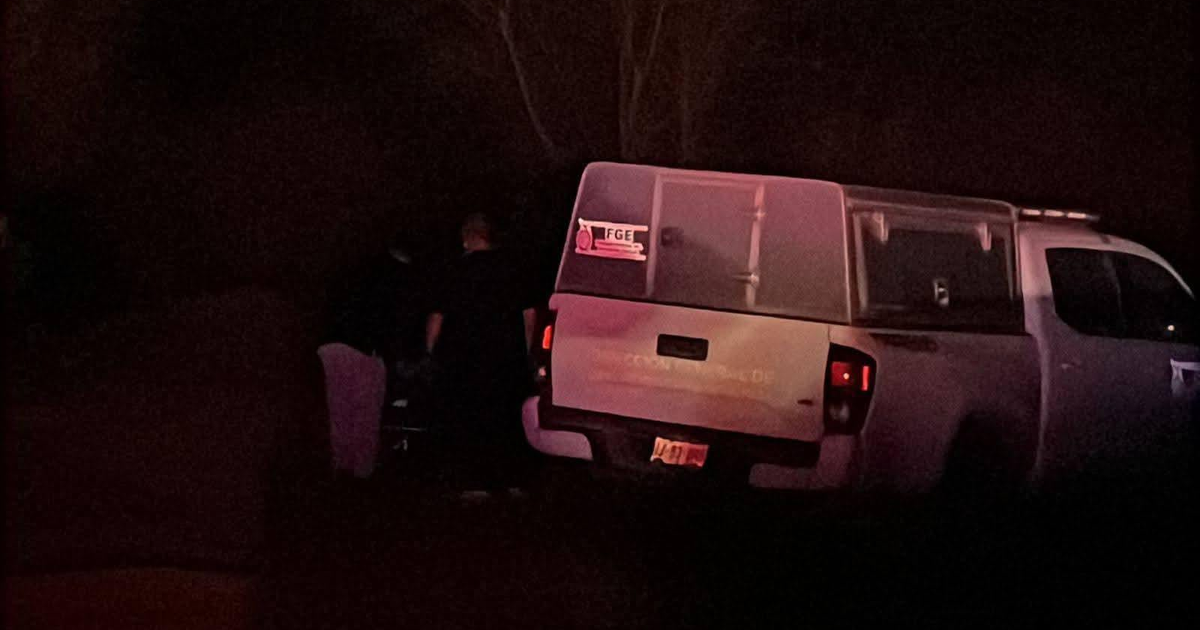 Camioneta blanca con caja cubierta y adhesivo 'FGE' en ambiente oscuro nocturno.
