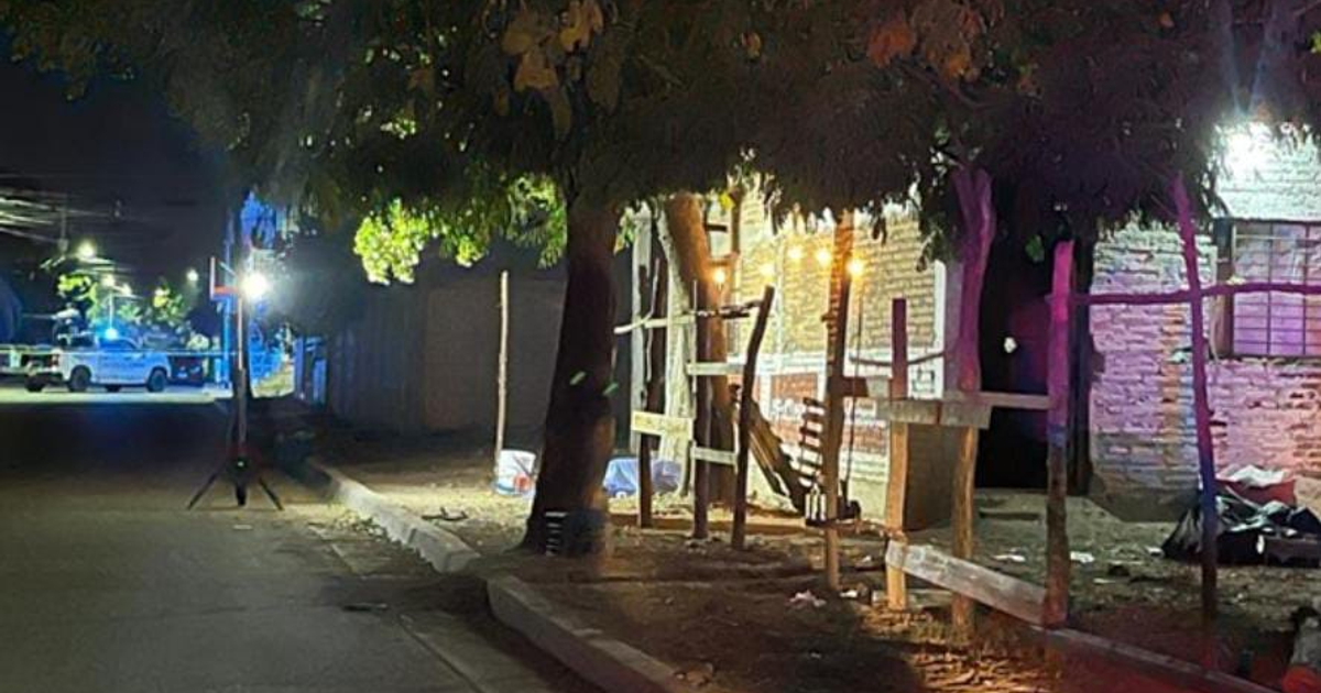 Policía en escena nocturna en Lomas de Tamazula; luces de emergencia azules y estructuras de madera visibles en la calle.