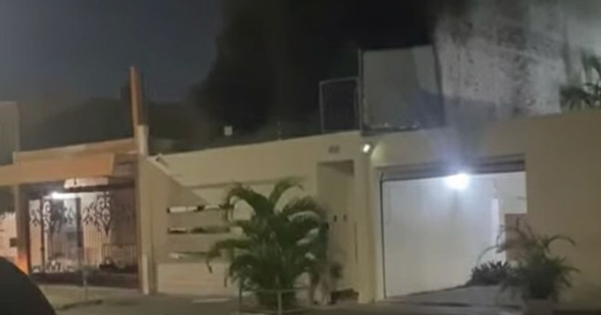 Casa iluminada de noche con garaje y planta en la entrada durante un incendio en Mazatlán
